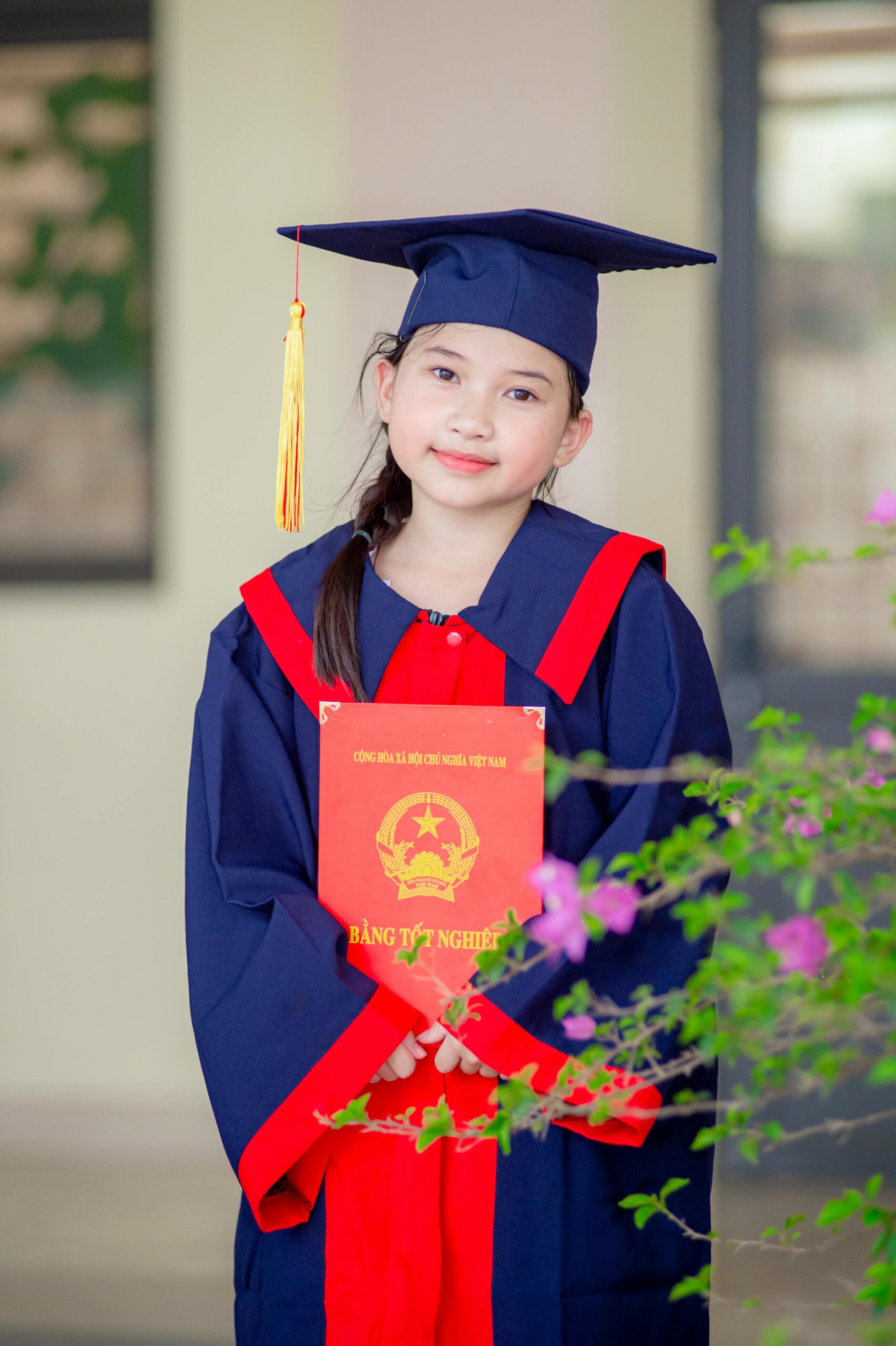 A young girl in graduation attire proudly holds her diploma in Hà Nội, Vietnam.